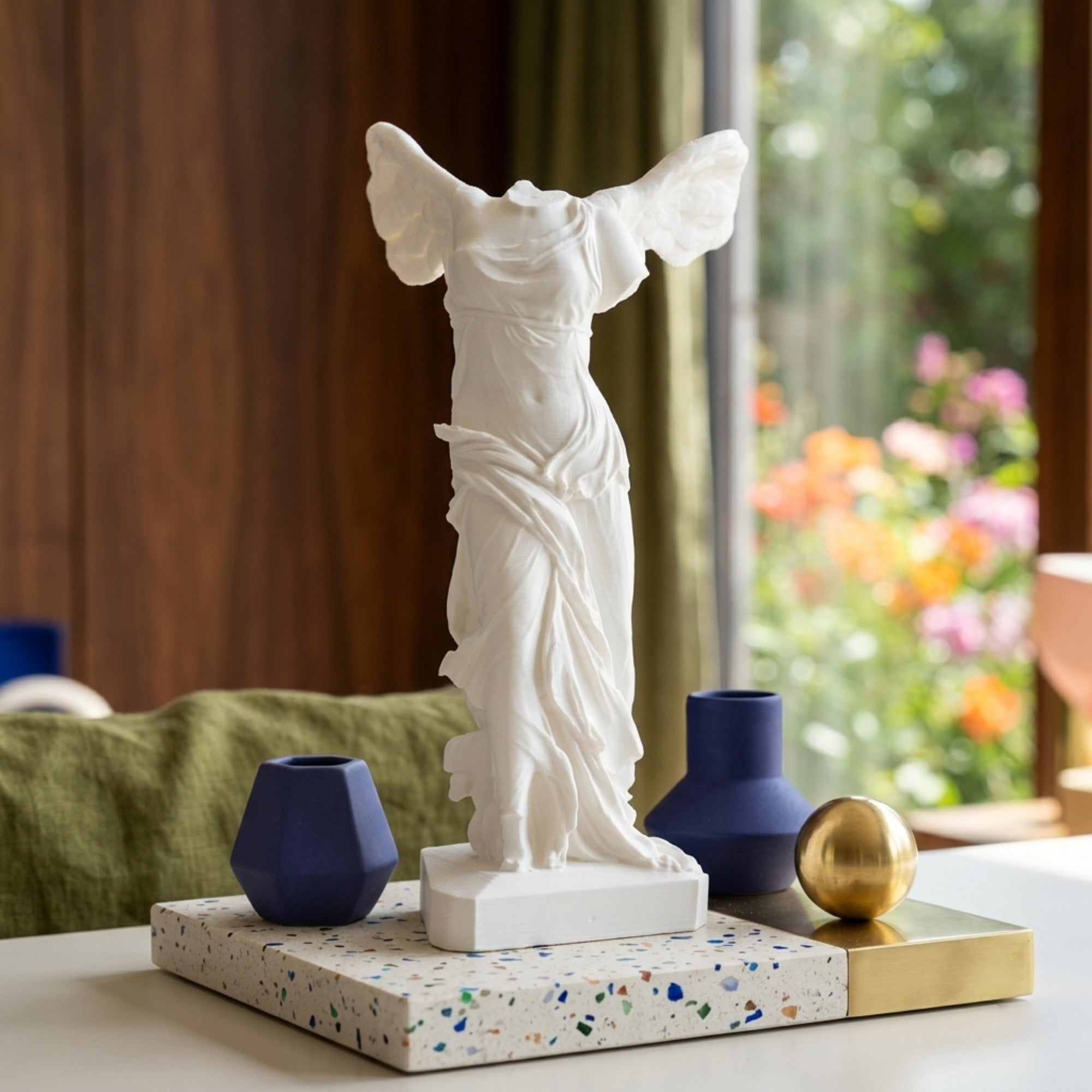 Statua Nike di Samotracia in stampa 3D su vassoio in terrazzo con decorazioni moderne.