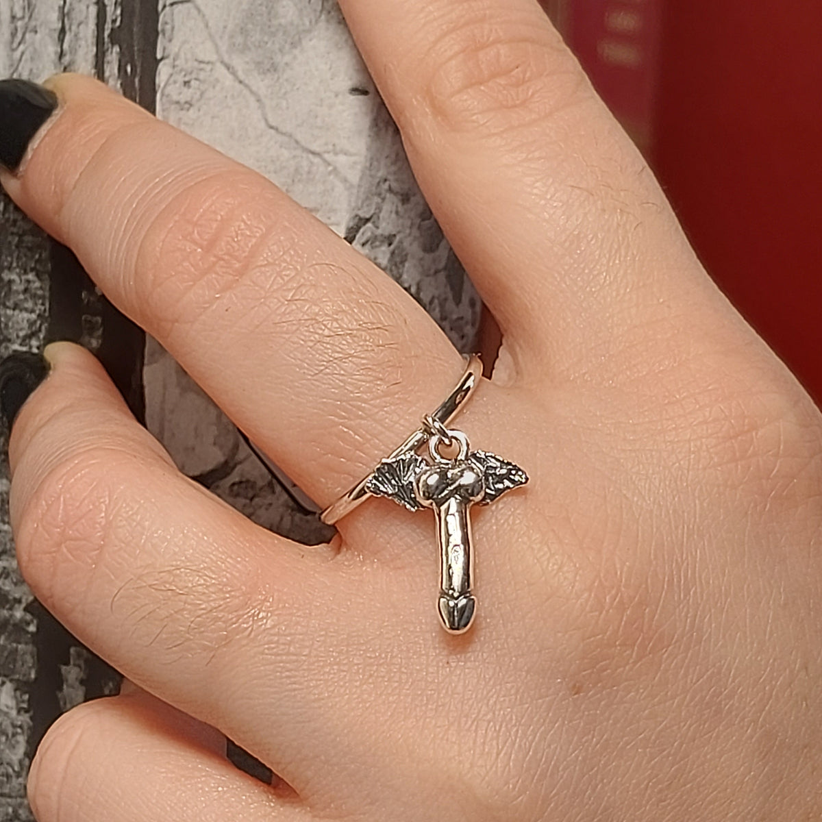 Dettaglio delle ali del pendente a fallo alato sull'anello in argento indossato