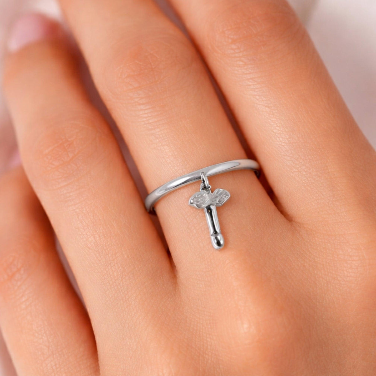 Primo piano dell'anello in argento con pendente a fallo alato indossato