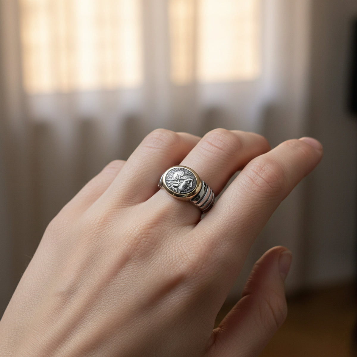 Anello in argento con riproduzione di moneta antica e bordo dorato, indossato sulla mano