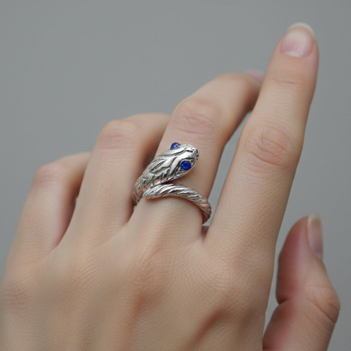 Anello a serpente in argento con occhi blu, indossato sulla mano