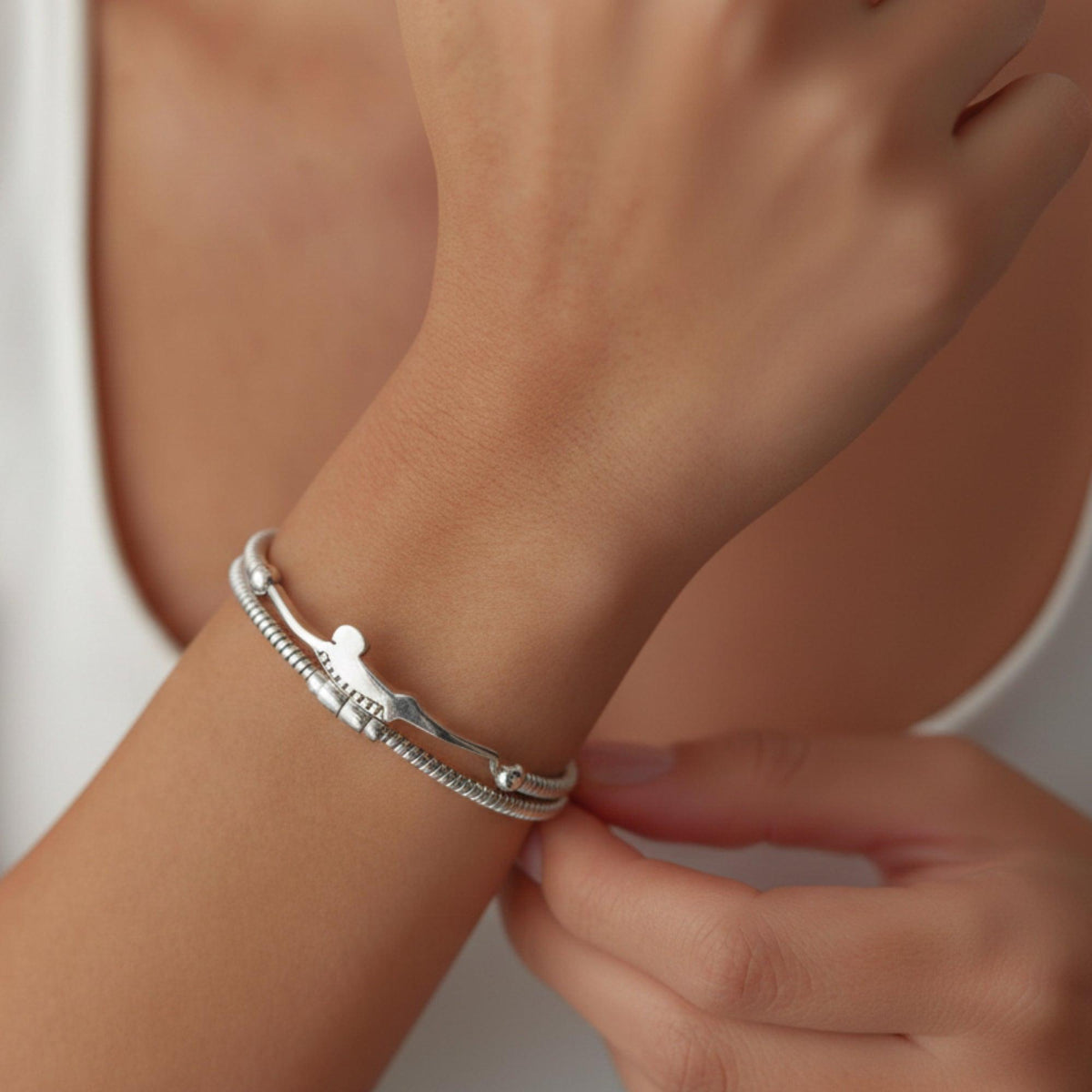 Bracciale in argento con sagoma del Tuffatore di Paestum, indossato al polso davanti a una canotta bianca
