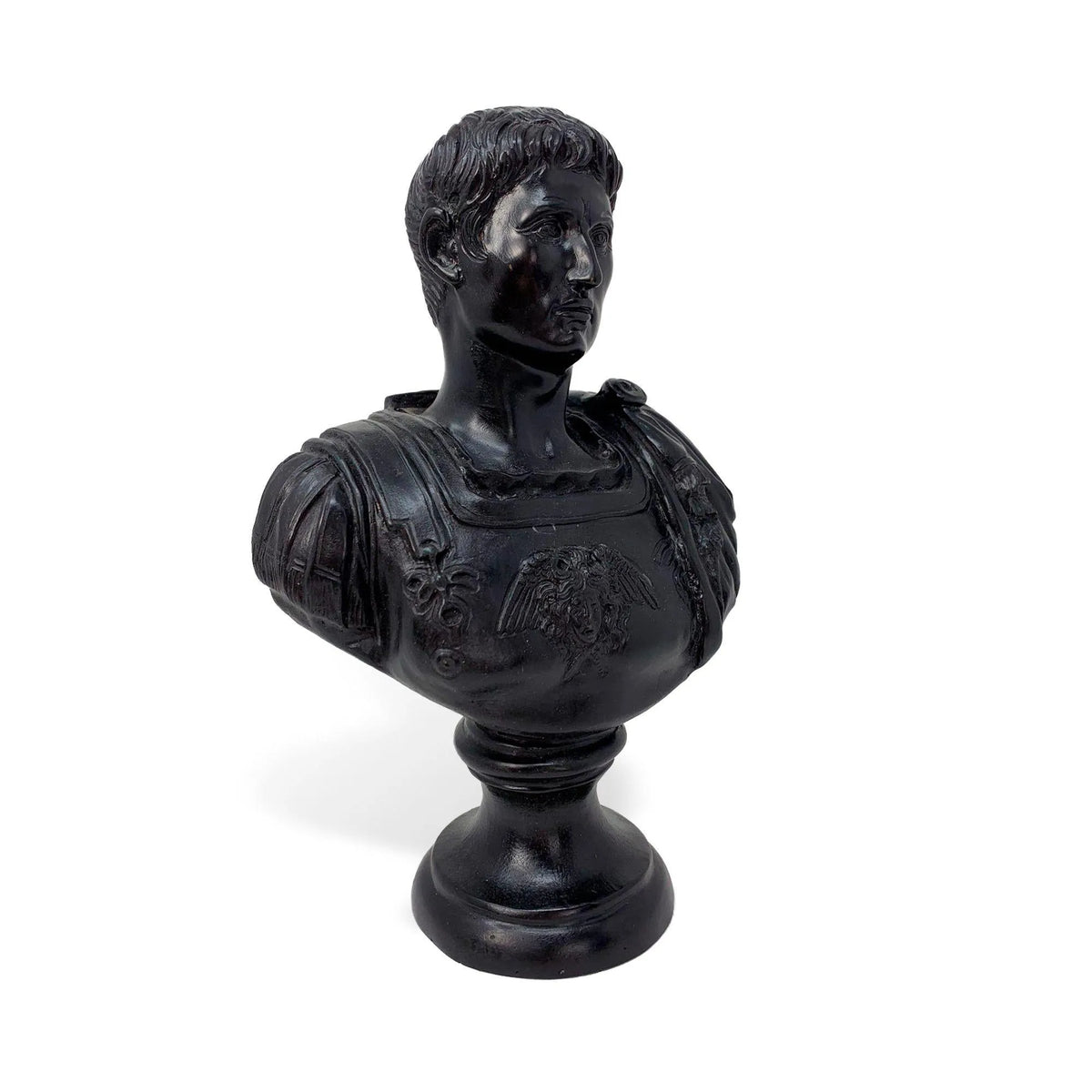 Busto in bronzo scuro dell’imperatore romano Augusto, fotografato di tre quarti con capelli scolpiti, corazza decorata e base rotonda.