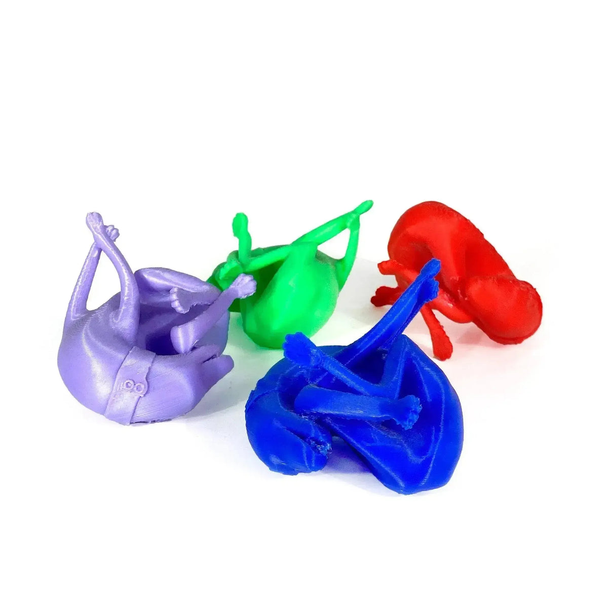 Quattro repliche del calco del cane di Pompei in PLA viola, verde, blu e rosso, su fondo bianco.