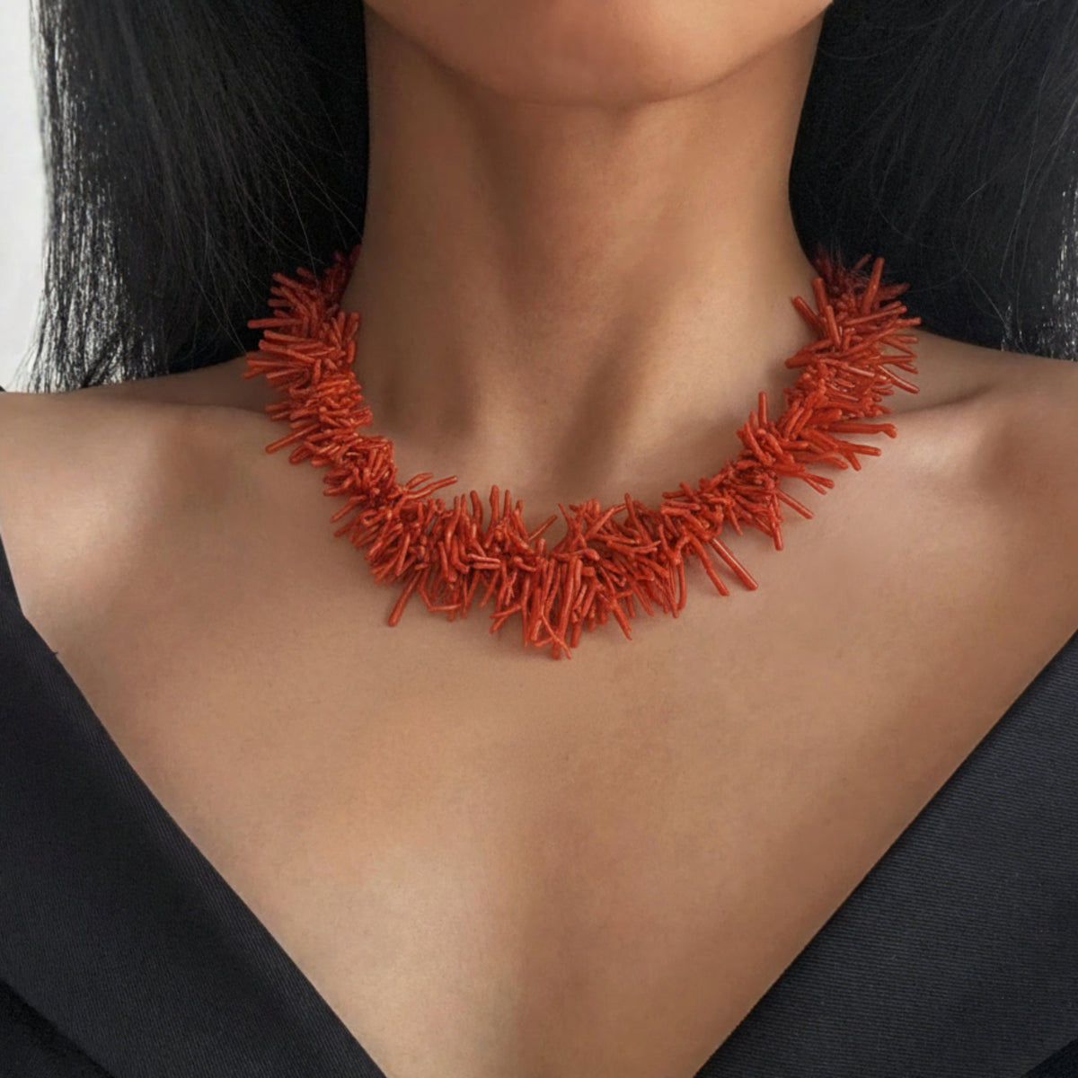 Collana di rami di corallo rosso indossata su un abito nero