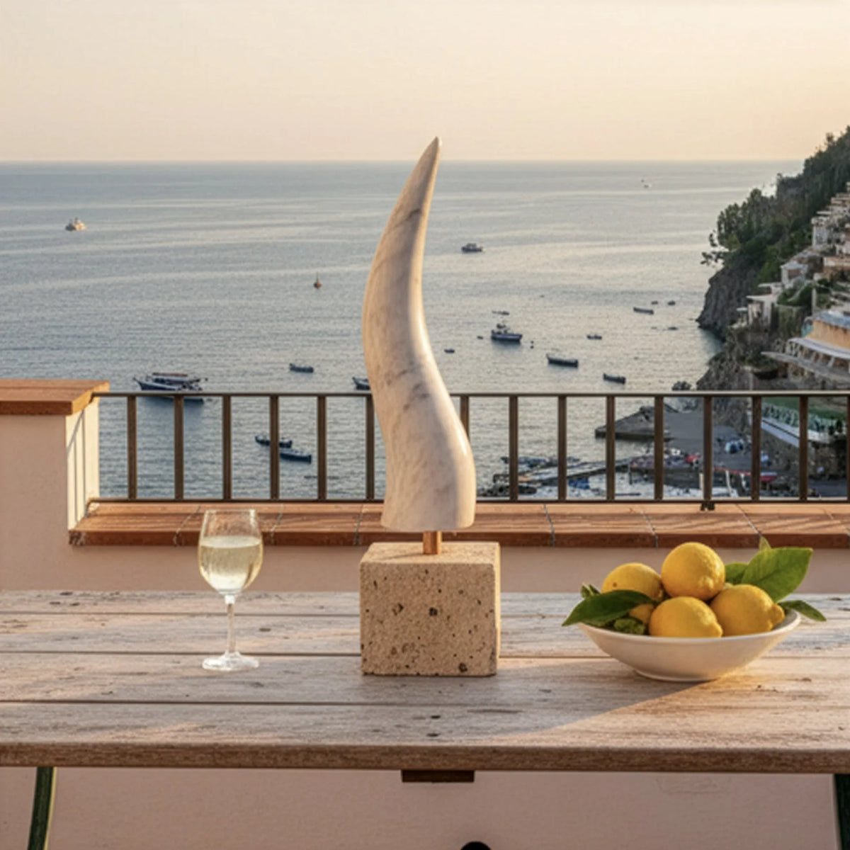 Corno in marmo di Carrara con base in tufo su un tavolo in pietra, su una terrazza affacciata sul mare