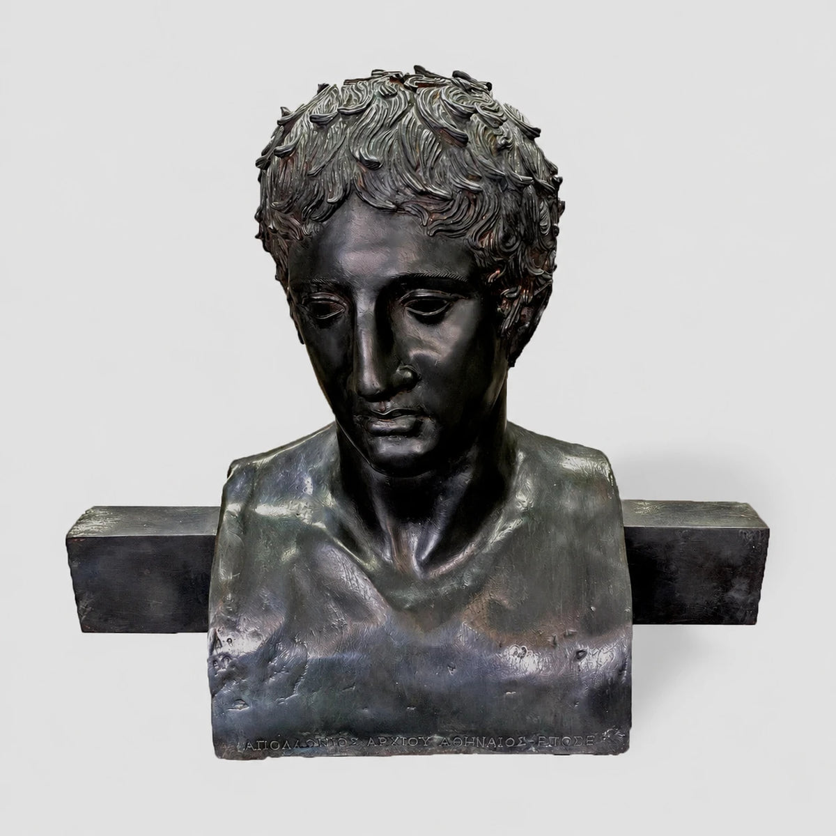 Erma di Doriforo, busto in bronzo con patina scura, vista frontale su sfondo grigio chiaro.
