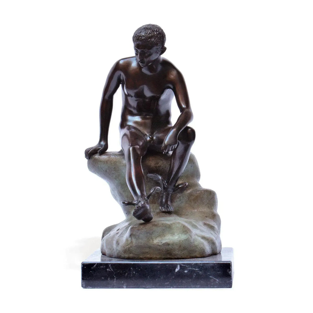 Hermes a riposo in bronzo scuro, statua decorativa con figura seduta su roccia, sandali alati e base in marmo, fotografata frontalmente su fondo bianco.