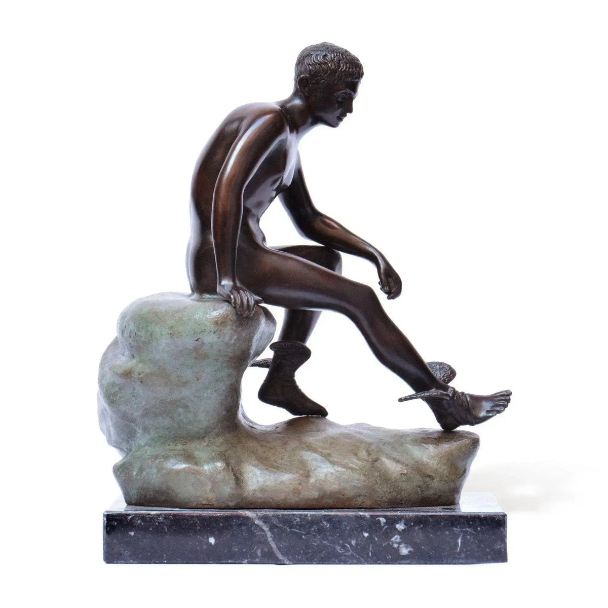 Hermes a riposo in bronzo scuro, statua decorativa fotografata lateralmente con figura seduta su roccia, sandali alati e base in marmo.