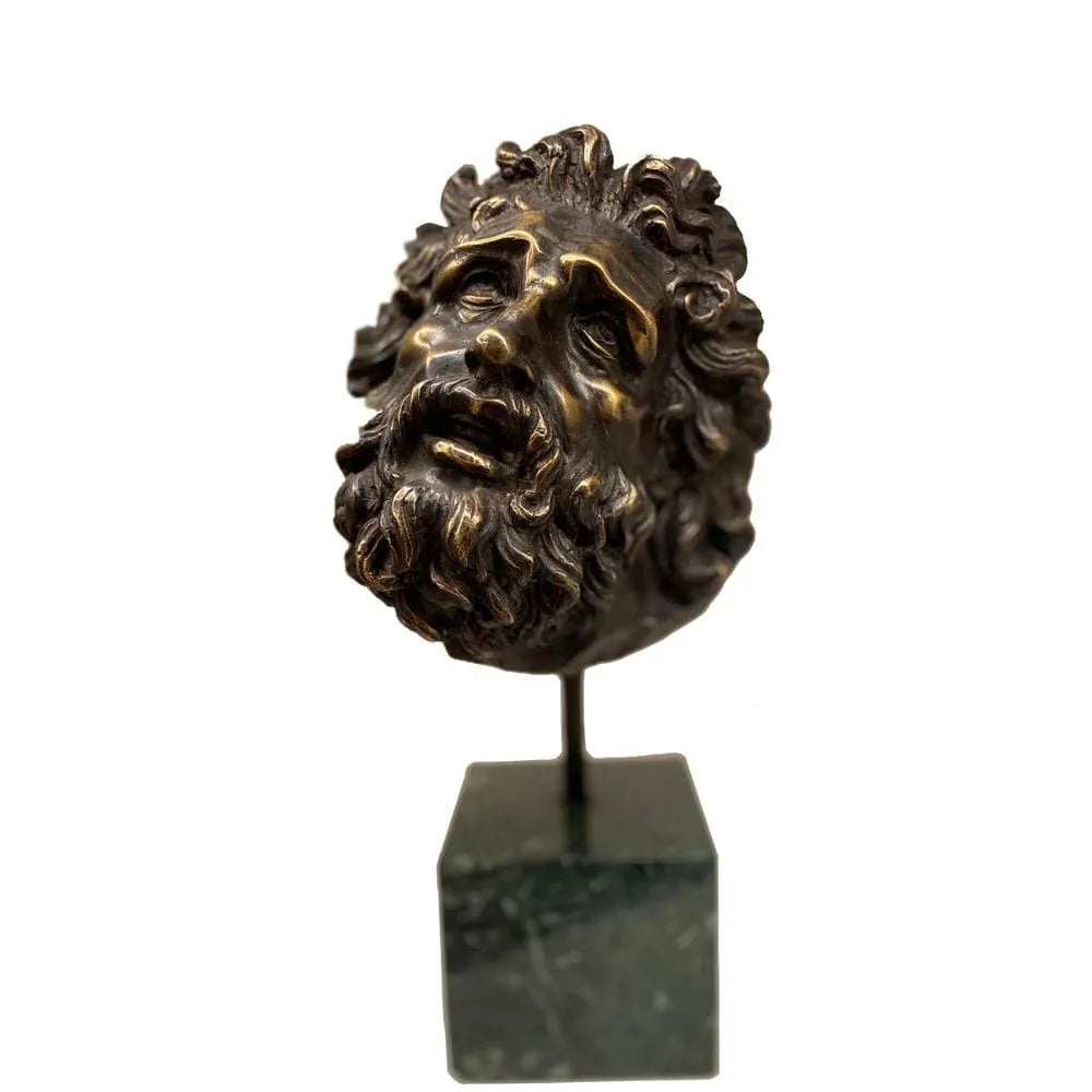Testa del Laocoonte in bronzo su base in marmo verde, con barba scolpita, capelli ricci e dettagli espressivi del volto su fondo bianco.