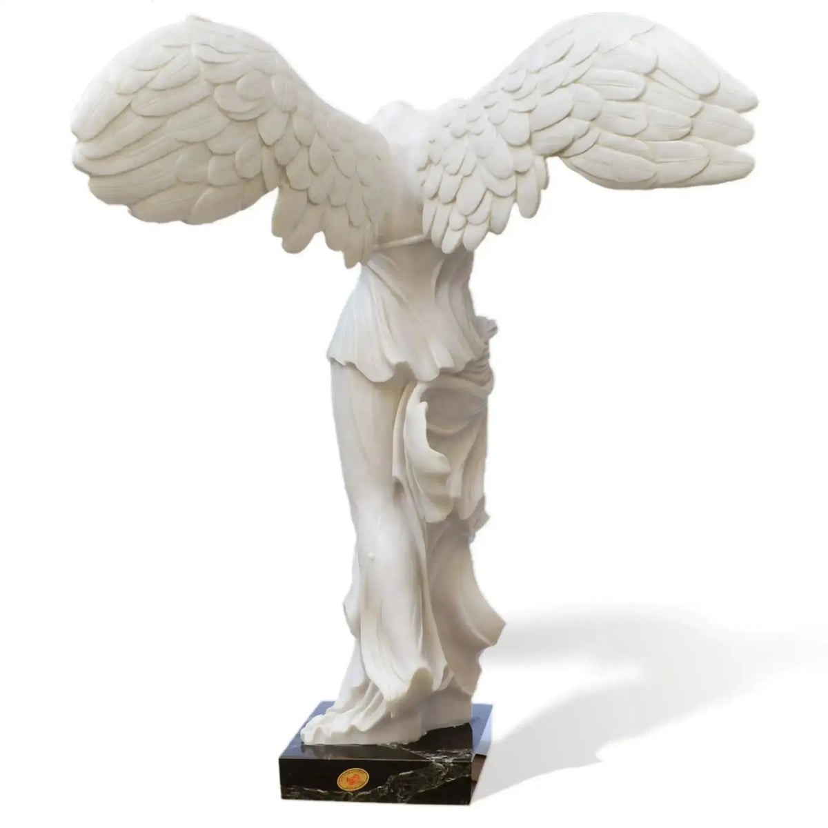 Vista trasera de la Victoria Alada de Samotracia que muestra las alas detalladas y las cortinas traseras de la estatua de mármol.