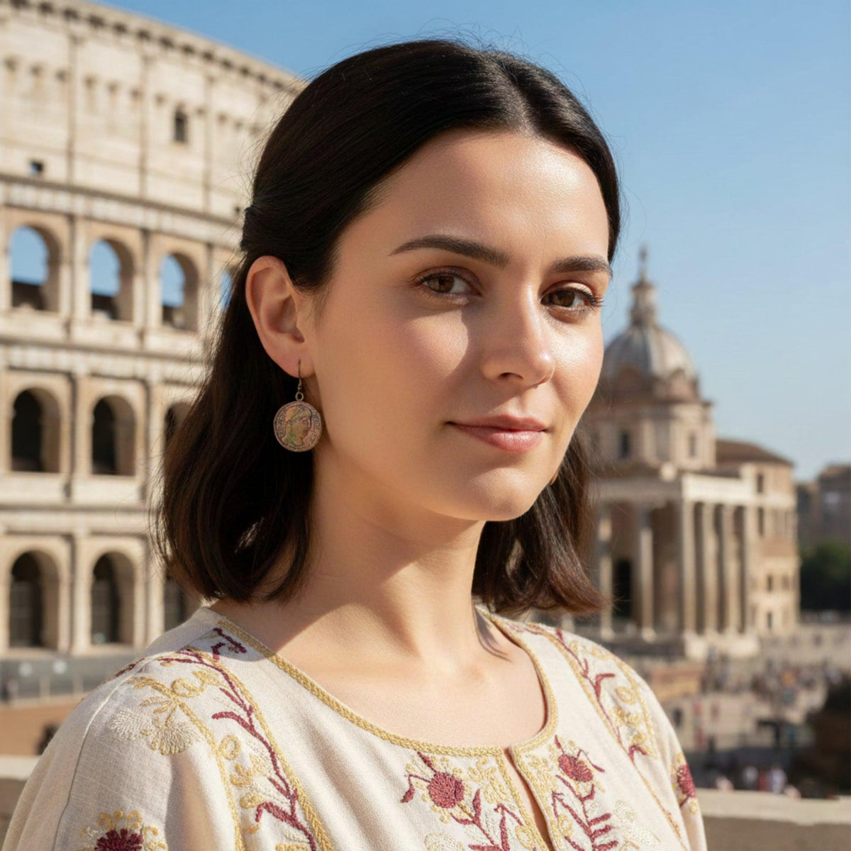 Orecchini a moneta in argento brunito, indossati con una maglia chiara ricamata