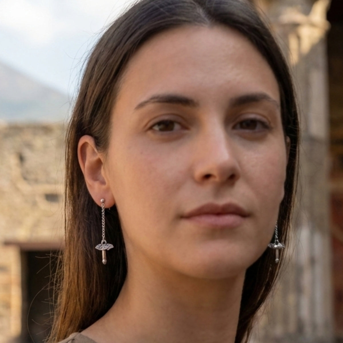 Orecchini pendenti in argento con fallo alato e catenelle, indossati