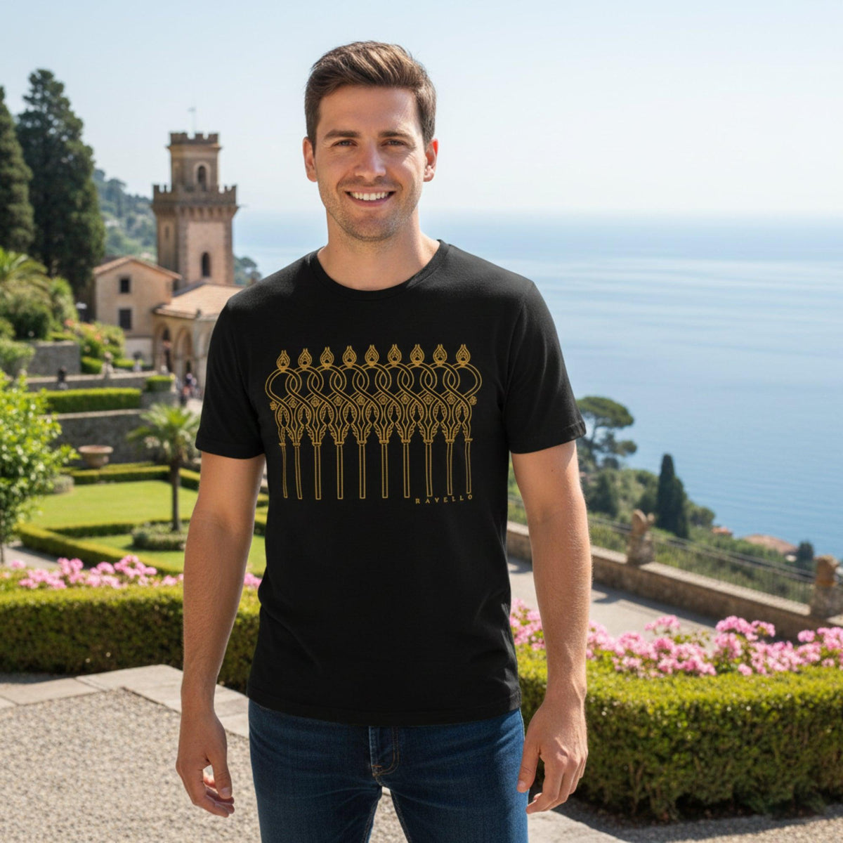T-shirt nera da uomo con motivo dorato di archi intrecciati, indossata in un giardino con vista sul mare.