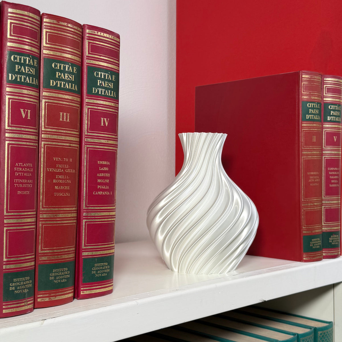 White vase on shelf with books