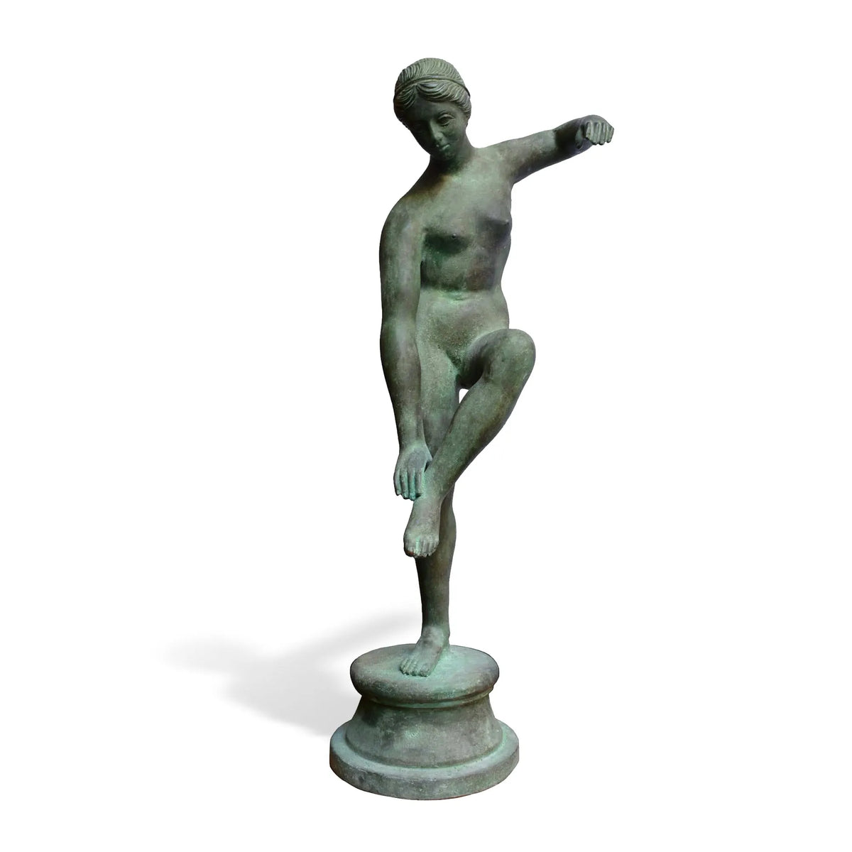 Venere al bagno in bronzo con patina verde e gamba sollevata, su base rotonda e fondo bianco.