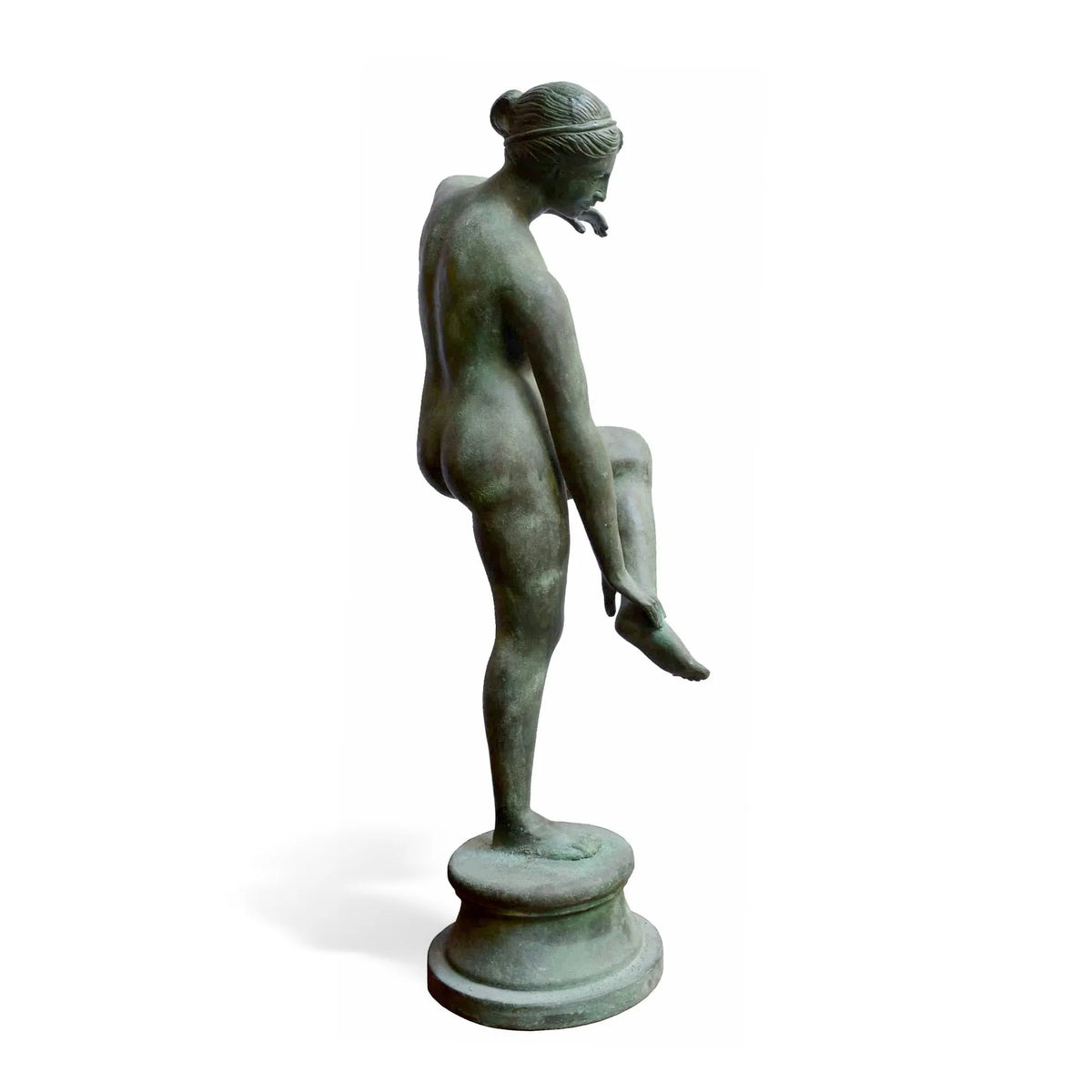 Venere al bagno in bronzo con patina verde, vista laterale con la gamba sollevata su fondo bianco.