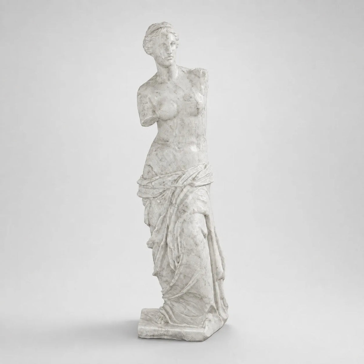 Venere di Milo in marmo di Carrara, vista frontale su fondo grigio chiaro.