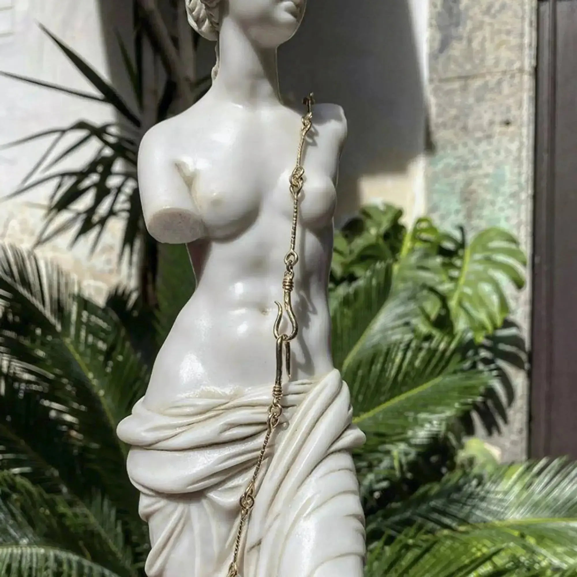 Statue en marbre de Vénus de Milo élégamment placée dans un jardin.